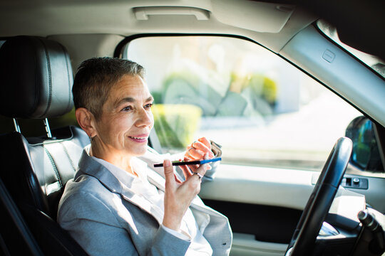 Smiling senior businesswoman using voice assistant in car
