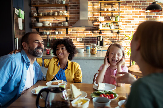 Happy family laughing together at breakfast in cozy home kitchen