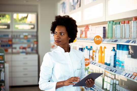 Female pharmacist using tablet in retail pharmacy aisle
