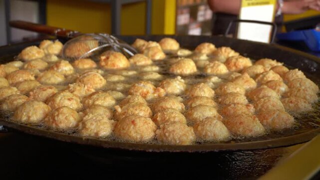 Close Up Sizzling Fried Meatballs Process in Large Wok with Boiling Oil
