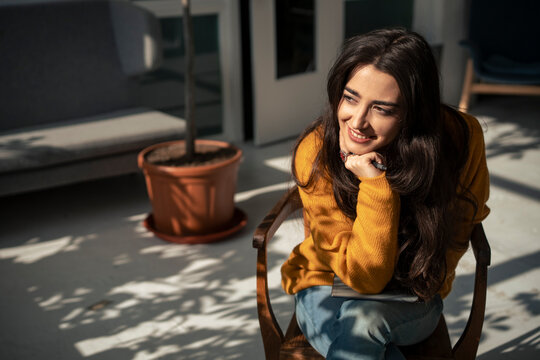 Smiling woman leaning on elbow and sitting on chair