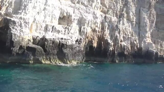 The ship sails past endless white cliffs, beneath which sea caves appear. The water churns beneath the ship and recedes. The sun is beautifully reflected in the water, sparkling