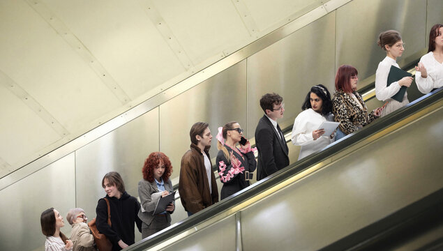 People standing on escalator in subway station forming line during daily commute. Concept of routine behavior, urban mobility, passive movement, time management, structured public transport system.