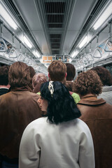 Crowded subway interior from behind with packed passengers during peak hour commute. Concept of anonymity, mass movement, urban pressure, limited space, and everyday commuting experience.