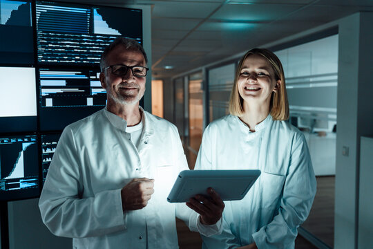 Smiling doctors holding tablet for data analysis in hospital