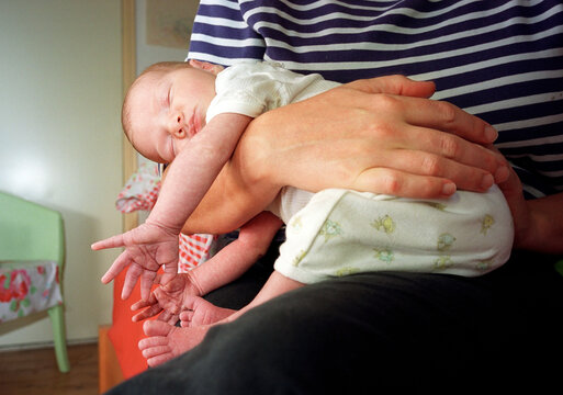 Baby sleeping on the lap of mother indoors in the Netherlands