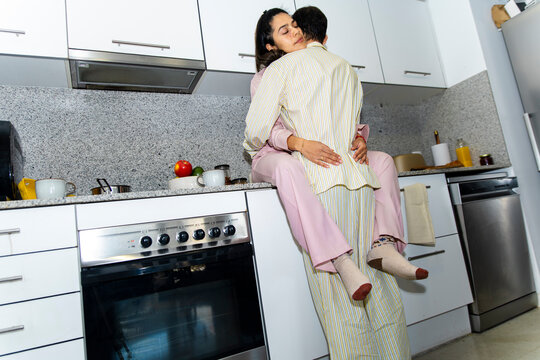 Couple hugging in pajamas in the kitchen at home