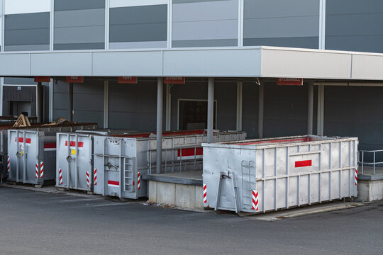 Waste containers in front of a large building at a loading area