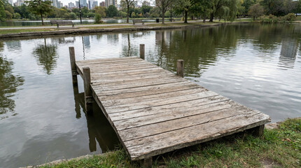 Obraz premium Wooden dock by tranquil park lake surrounded by trees 