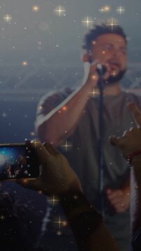 Vertical video: Fan holding phone, starting recording to capture singer singing amid concert lights