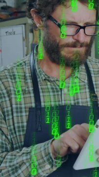 Vertical video: Maker tapping tablet, causing green binary overlay in workshop while checking plan