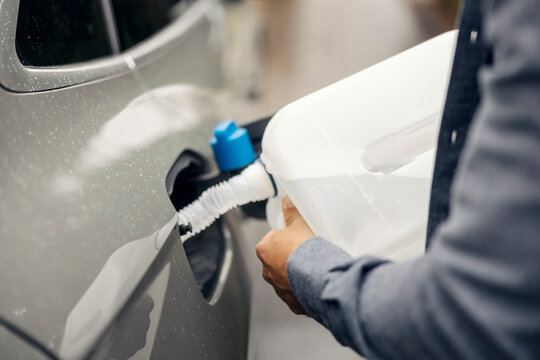 Person filling diesel exhaust fluid in a modern car