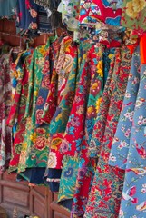 Fototapeta premium Vibrant traditional Chinese quilted floral jackets known as Dong Bei Da Hua on display in Dali Market, Yunnan, China on October 20, 2017.