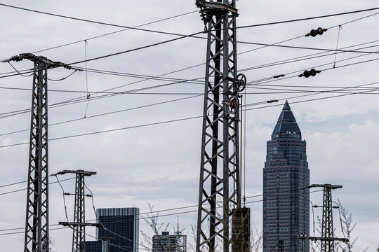 Industrial infrastructure spans Frankfurt where powerlines electricity grid pylons and engineering frame the city skyline supporting industry