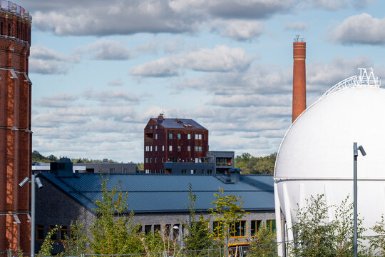 Modern industry facility near the Stockholm skyline shows factory refinery storage tank infrastructure with a smokestack shaping industry