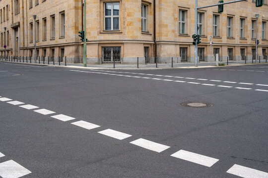 Empty urban street intersection with crosswalk on the road next to building architecture in daylight creating a clear scene and usable copyspace