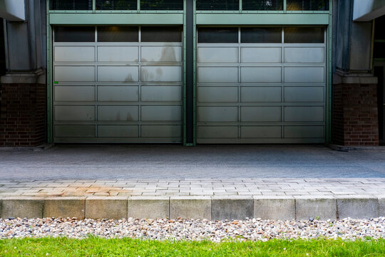 Closed industrial garage door set in an urban facade with concrete wall and minimal empty composition delivering strong copyspace for service themes
