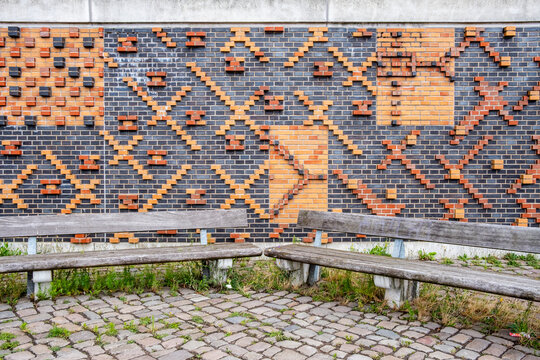Abstract urban wall mural with brick pattern texture behind a bench beside sidewalk pavement offering clean copyspace for modern design layouts