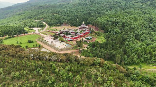 High angle aerial shot of the historic Fuguo Monastery and surrounding forest landscape in Yunnan. Perfect for travel documentaries and cultural heritage content.