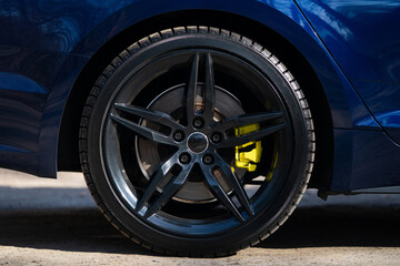 Obraz premium Close-up of a black multi-spoke wheel with a yellow brake caliper