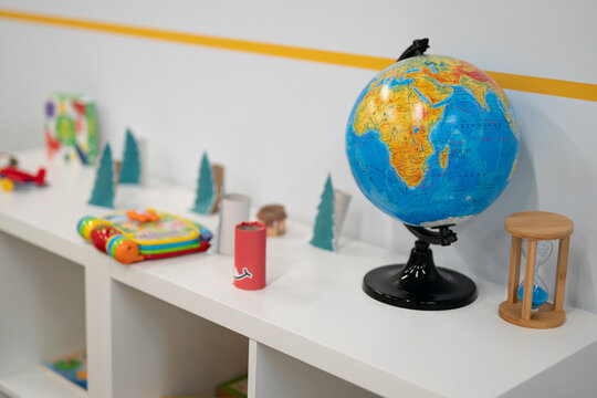 Educational toys including a globe and hourglass on a white shelf