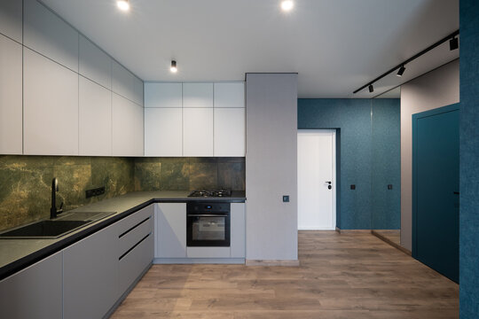 Modern open-plan kitchen and hallway with minimalist grey cabinetry and blue accents