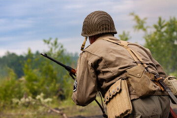 Obraz premium Reconstruction of battle from the Second World War. American infantry soldier during combat. View from the back