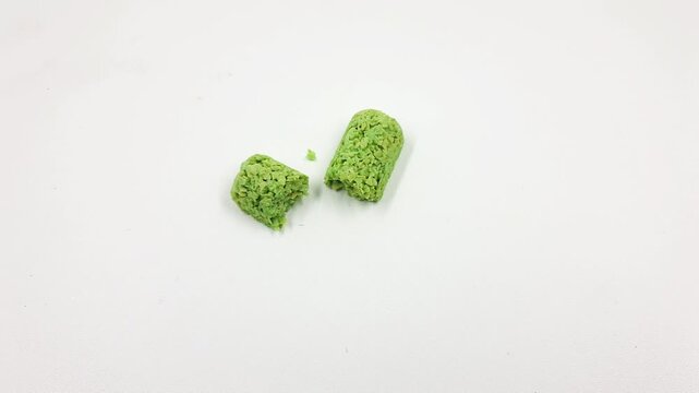 Green crumbled protein supplement chunks resting on a white background video