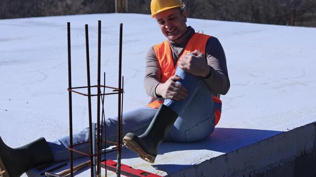 Construction worker having a accident and injured knee and leg on a construction site outdoors.