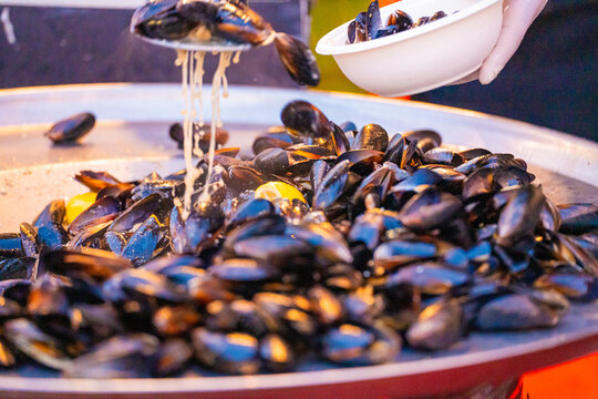 View of glistening mussels cascade from a white bowl, their dark shells contrasting with creamy sauce, a seafood symphony on a silver platter, Pula, Istria County, Croatia.
