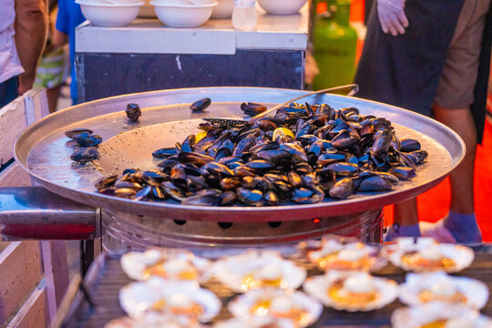View of glistening mussels piled high on a large metal platter, juxtaposed with rows of scallop shells, creating a feast for the eyes, Pula, Istria County, Croatia.