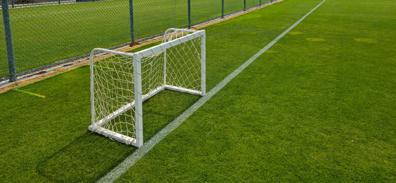 Small White Soccer Goal on Green Turf Field Near Chain Link Fence for Youth Practice