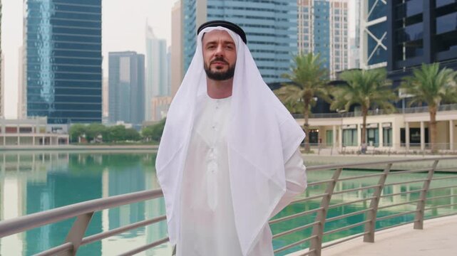 Portrait of a confident Arab businessman, sheik in Arabian Gulf traditional clothing, kandura and ghutra, posing at the Dubai Marina.