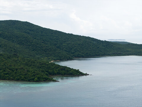 Aerial view of the lush, green island meeting the tranquil turquoise sea, a serene escape where nature's palette blends seamlessly, Karimunjawa, Central Java, Indonesia.