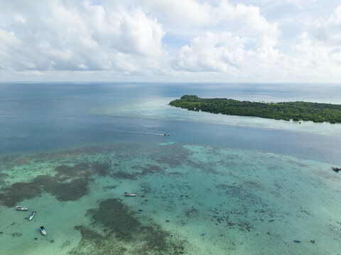 Aerial view of turquoise waters meeting the lush green shores of a tropical island paradise, Karimunjawa, Central Java, Indonesia.