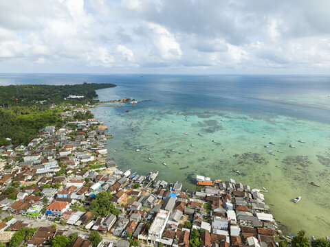 Aerial view of the vibrant coastal village where the earthy tones of the rooftops meet the turquoise embrace of the sea, Karimunjawa, Central Java, Indonesia.