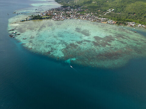 Aerial view of turquoise waters meet the shore, revealing a vibrant reef system contrasting with the deep blue ocean, Karimunjawa, Central Java, Indonesia.