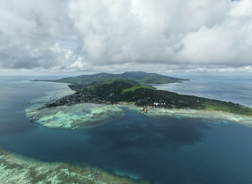 Aerial view of the island's contrasting deep blues of the ocean and the bright turquoise shallows meet the lush green landscape, Karimunjawa, Central Java, Indonesia.
