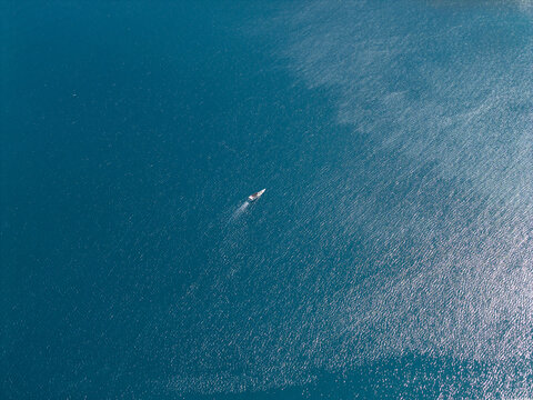 Aerial view of a lone boat cutting through the turquoise waters, leaving a white wake behind, Karimunjawa, Central Java, Indonesia.