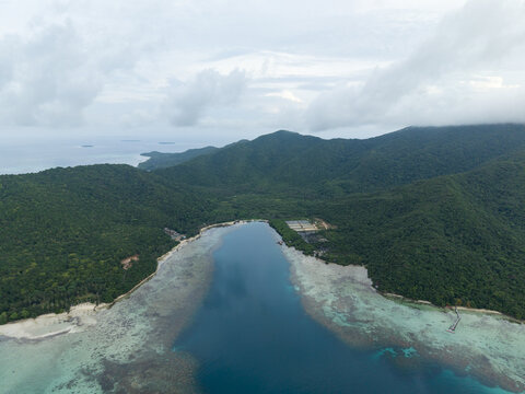 Aerial view of the tranquil waters meet the lush, green coastline under a cloudy sky, Karimunjawa, Central Java, Indonesia.