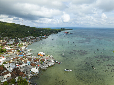 Aerial view of the village nestled along the coast where the turquoise sea meets the land, a vibrant contrast of colors, Karimunjawa, Central Java, Indonesia.