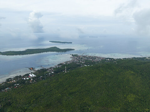 Aerial view of the coastline meeting the lush greenery, houses nestled along the shore, and islands dotting the horizon, Karimunjawa, Central Java, Indonesia.