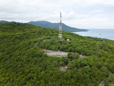 Aerial view of the verdant landscape crowned by a towering telecommunications mast, overlooking the tranquil sea, Karimunjawa, Central Java, Indonesia.