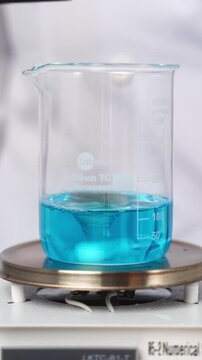 Magnetic stirrer mixing blue copper sulfate solution in a beaker during a chemical laboratory experiment