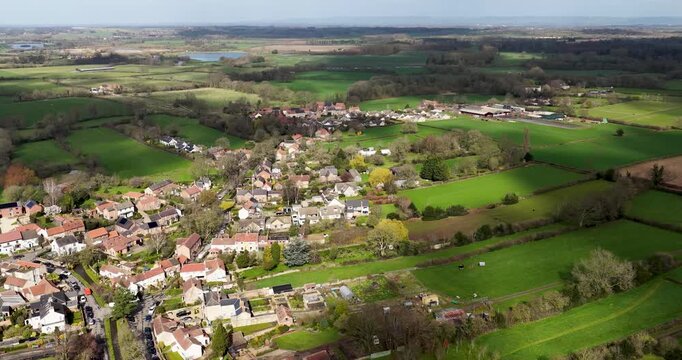 Aerial drone footage of Bishop Monkton showing stone houses gardens trees and a quiet residential road with surrounding farmland in a peaceful North Yorkshire village setting in the spring time