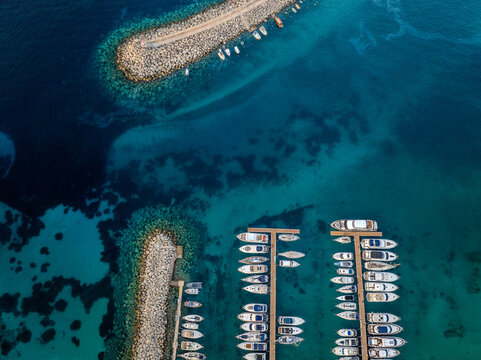Aerial view of boats docked in the marina, contrasting against the azure waters surrounding the harbor, Mgarr Harbour, Gozo, Malta.