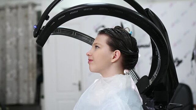 Professional hair treatment with climazone device in beauty salon, modern infrared equipment for coloring, restoration and care, female client during procedure, advanced haircare technology