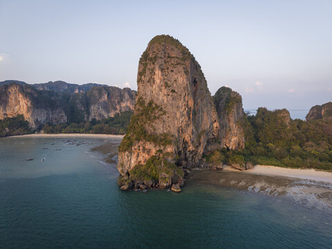 Aerial view of monolithic limestone cliffs jutting from the turquoise sea, fringed by beaches and lush greenery, Railay Beach, Thailand.