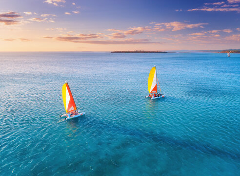 Aerial drone view of sailboats on blue sea at sunset in summer. Tropical landscape with boat, ocean with clear water, colorful sky. Yacht in the evening. Travel in Zanzibar, Africa. Vacation travel