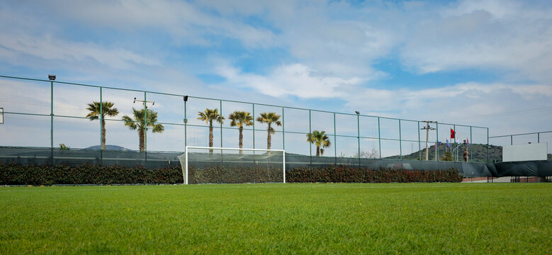 Soccer Goal on Lush Green Field With Palm Trees and Fenced Outdoor Sports Court